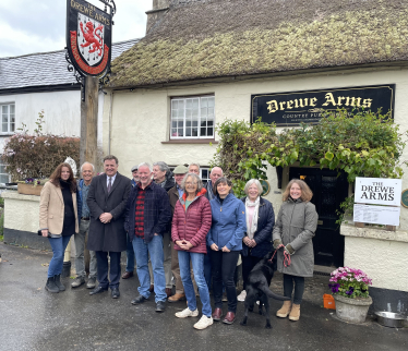 Mel Stride MP outside the Drewe Arms Pub with staff and customers.